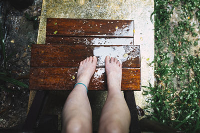 Low section of woman on wet wooden steps during rainy season