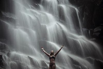 Woman standing against waterfall