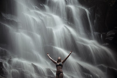 Full length of young woman standing in water