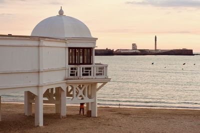 Built structure on beach against sky during sunset