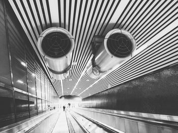 Low angle view of escalator in illuminated tunnel