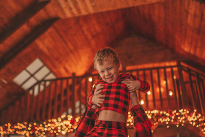 Candid authentic happy dad and son in red plaid pajamas fooling around at wood lodge xmas decorated