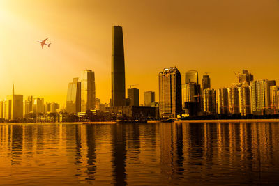 Modern buildings in city against sky during sunset