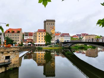 Bridge over river in city against sky