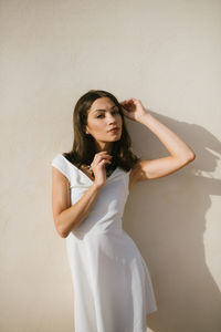 Portrait of young woman standing against wall