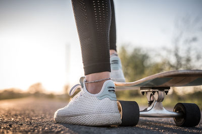 Low section of woman skateboarding on road