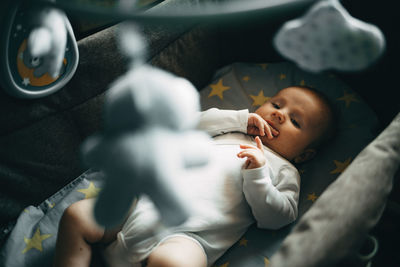 Baby boy lying down in cot at home