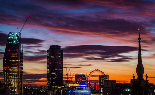 Illuminated buildings against cloudy sky at dusk