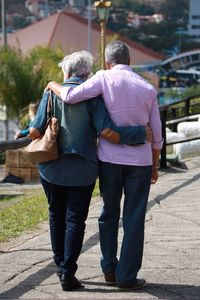 Full length rear view of senior couple walking on pathway