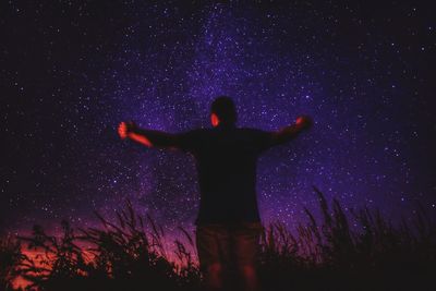 Rear view of man standing against star field at night