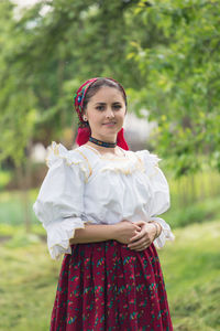 Portrait of beautiful young woman in romanian clothing standing at yard