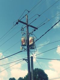 Low angle view of electricity pylon against cloudy sky