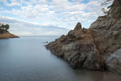 Rock formation by sea against sky