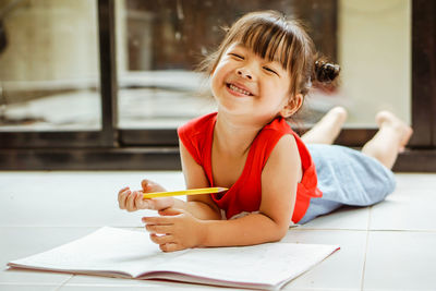 Portrait of girl lying with book on floor