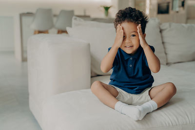 Full length of boy sitting on sofa at home