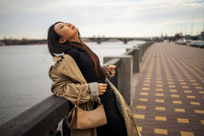 Asian woman in winter coat standing on city bridge dreaming and enjoying life