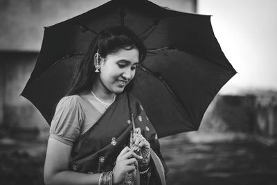 Portrait of a smiling young woman holding umbrella