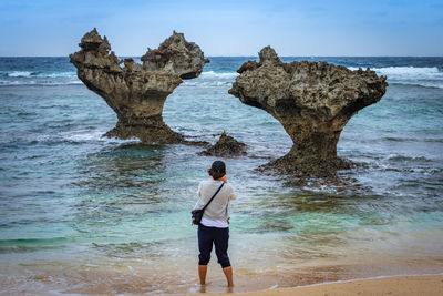 Rear view of man standing on rock at beach