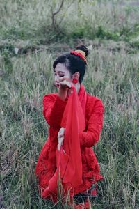 Young woman looking away while standing on field