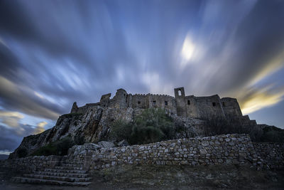 Low angle view of old building against cloudy sky