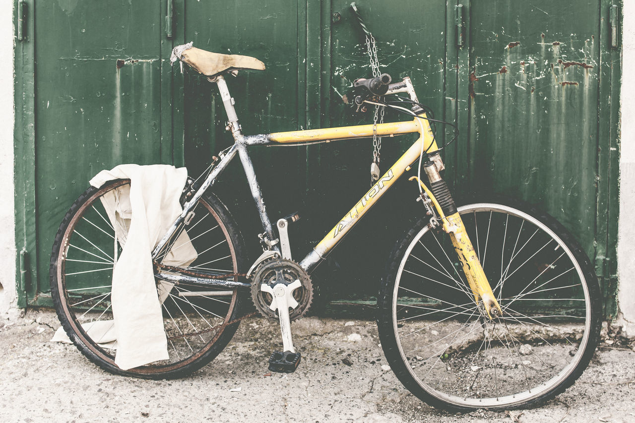 BICYCLE PARKED BY WALL