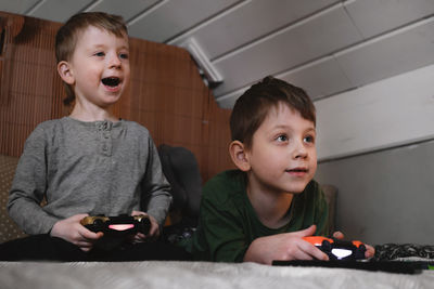Kids playing video games at home on the bed at night. boys using game console and having fun in the