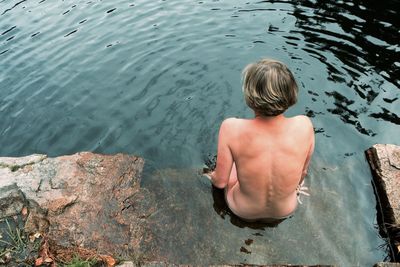 High angle view of naked woman sitting by lake