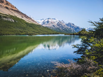 Scenic view of lake and mountains against clear blue sky