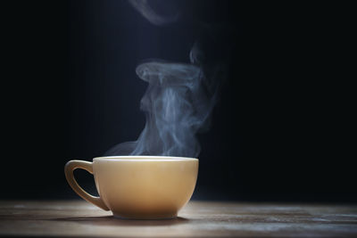 Close-up of coffee cup on table against black background