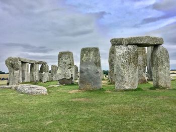 Stone wall on field against cloudy sky