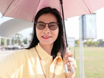 Portrait of woman holding umbrella while standing outdoors