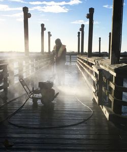 Man standing on bridge in city against sky