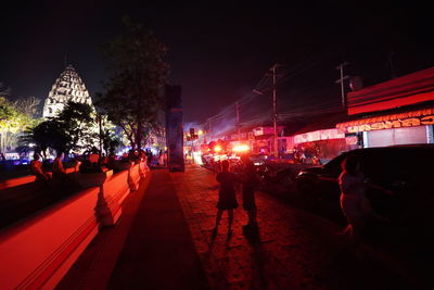 People walking on illuminated street in city at night