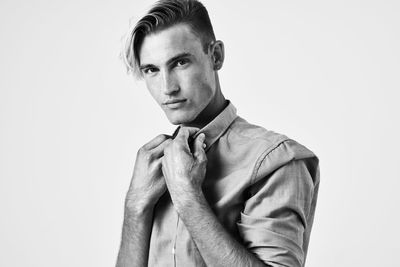 Portrait of young man standing against white background