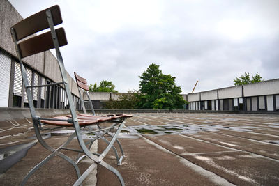 Empty chairs outside house against sky in city