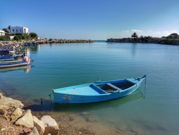 Boats moored on sea against clear blue sky