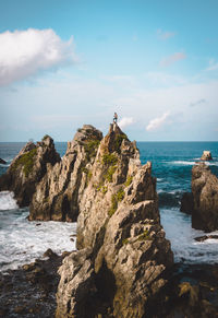 Man standing on rock formation against sea