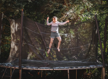 A beautiful caucasian girl in shorts and a t-shirt with sleeves jumps on a trampoline