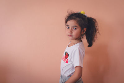 Portrait of a girl standing against wall