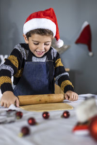 Smiling boy making cookies on table at home