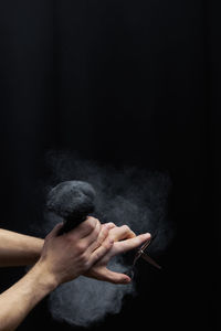 Cropped image of man holding brush against black background