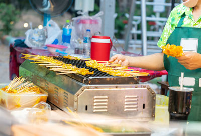 Pork satay seller grilling pork satay on an iron grill in street food market.