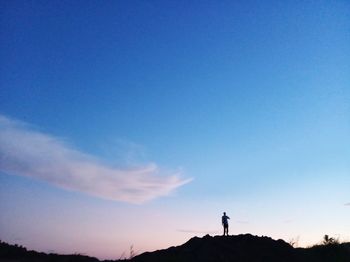 Silhouette man standing against blue sky