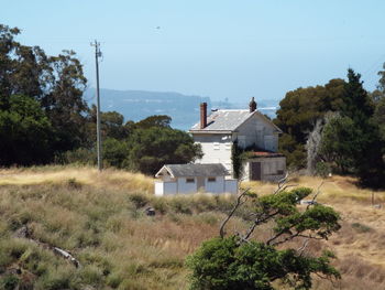 House on field by building against sky