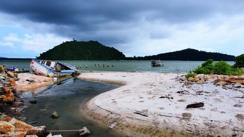 Boats in sea against cloudy sky