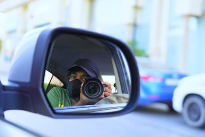 Reflection of man on side-view mirror of car