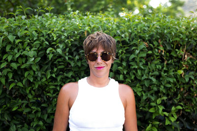 Portrait of man wearing sunglasses standing against plants
