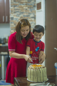 Mother and son cutting cake at home