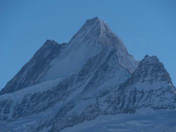 Low angle view of snow mountain against blue sky