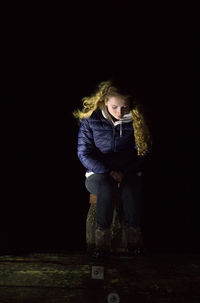 Girl looking away while standing against black background